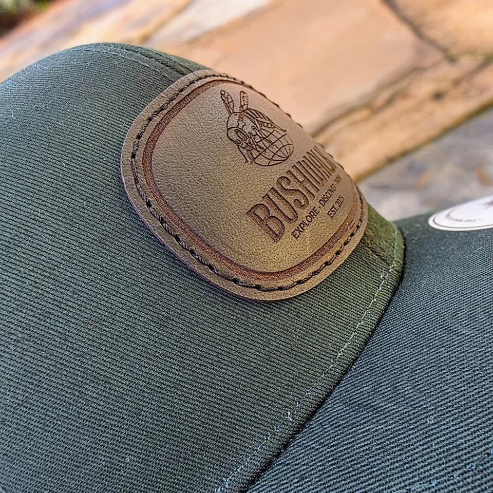 Tonal laser engraving on a brown leather patch, on a dark green cap