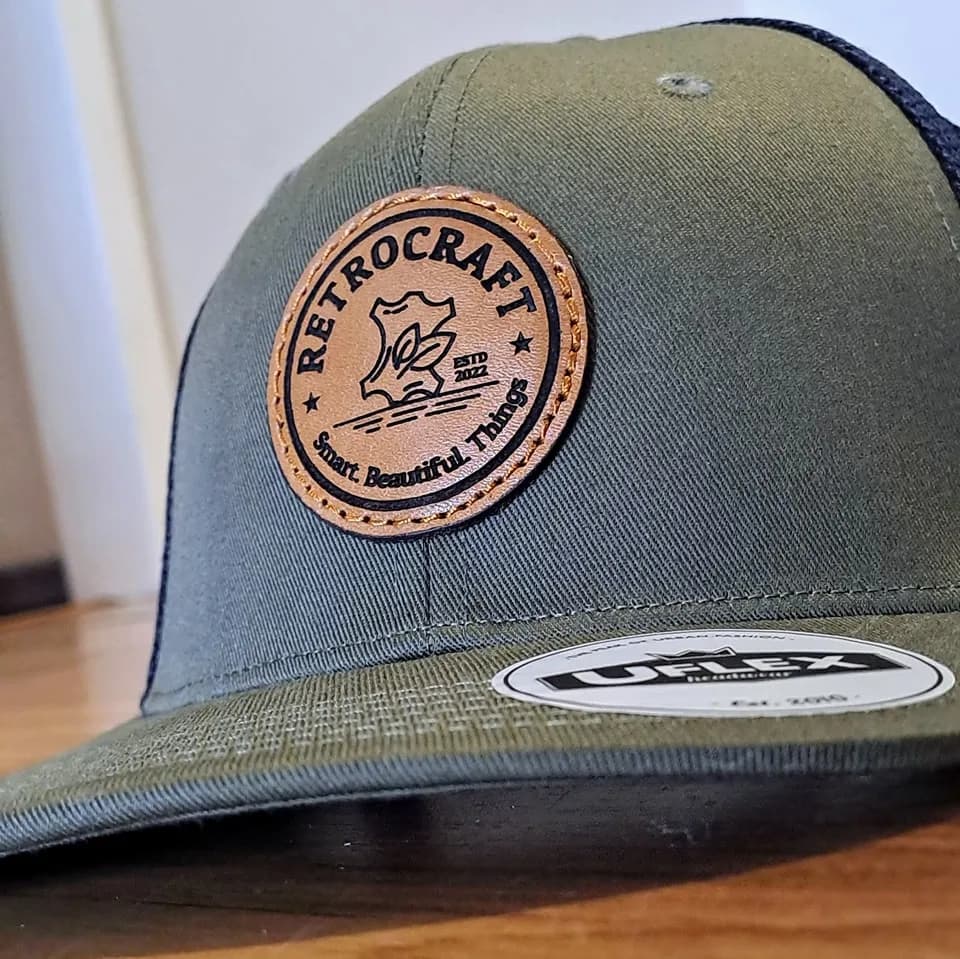 Round engraved leather patch on an olive trucker cap