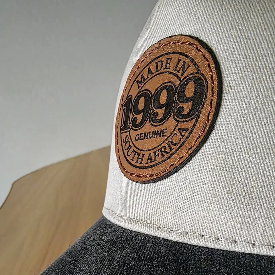 Round leather patch on a stone trucker cap, seen from the side