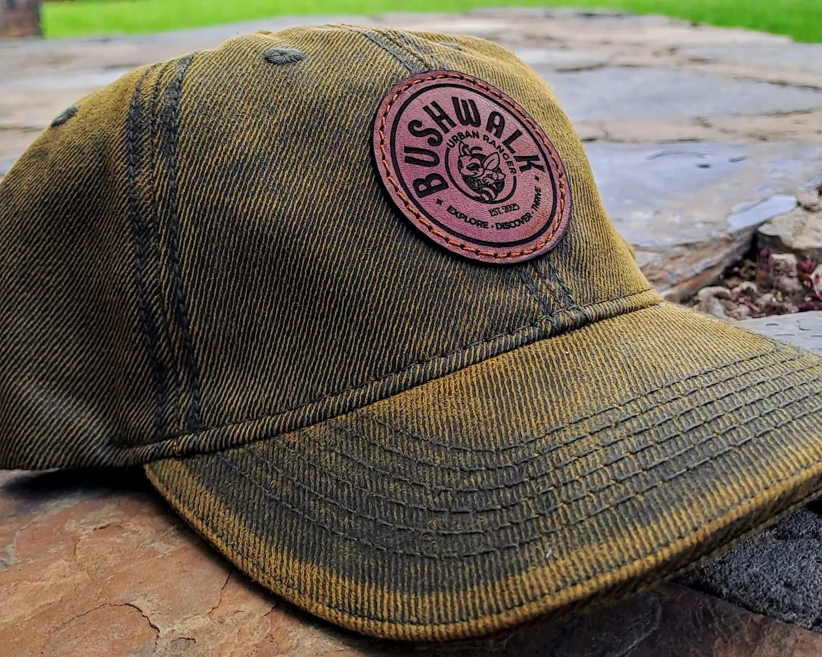 Round engraved leather patch on a waxed olive cap